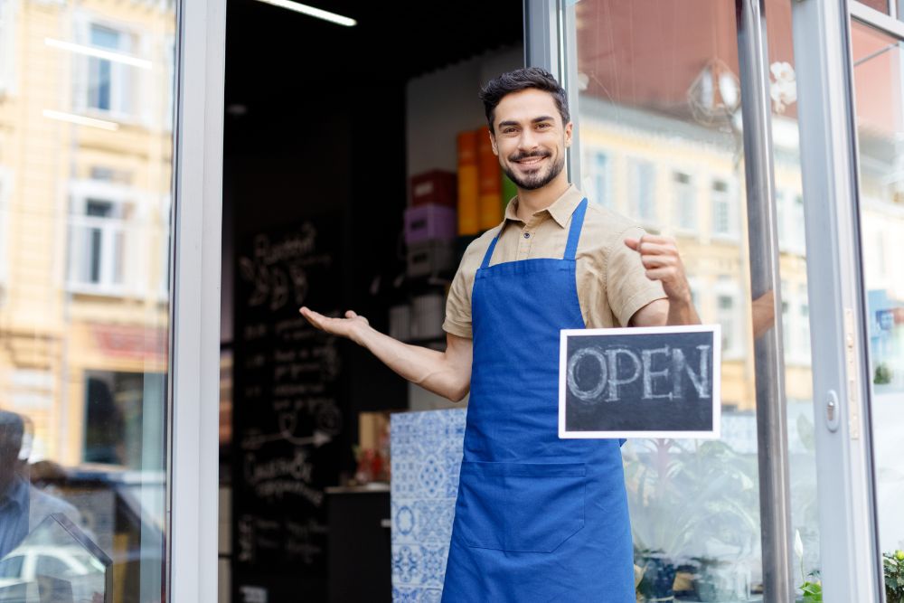 Small business owner standing outside shop with open sign